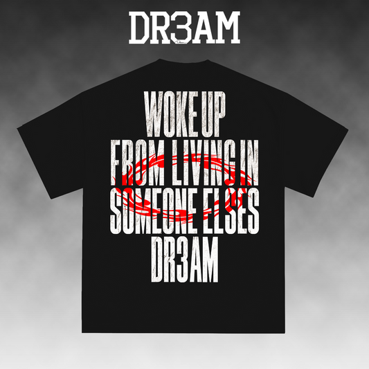 A black short-sleeve t-shirt with a bold graphic print on the front. The design features distressed white text reading 'WOKE UP FROM LIVING IN SOMEONE ELSE'S DR3AM' with a red scribble graphic crossing out 'LIVING IN'.