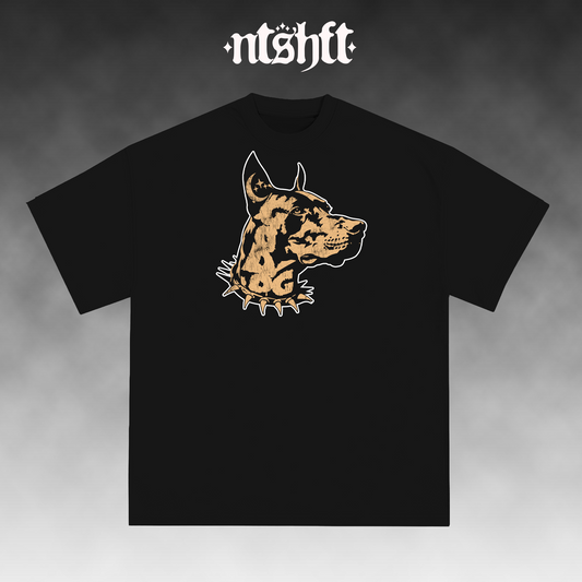 A black short-sleeve t-shirt with a stylized graphic of a dog's head in tan and white on the chest. The brand name 'ntshft' is printed in a white gothic font at the top of the image, set against a dark gray gradient background.